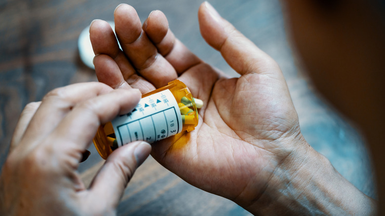 A man taking pills and pouring them into his hand