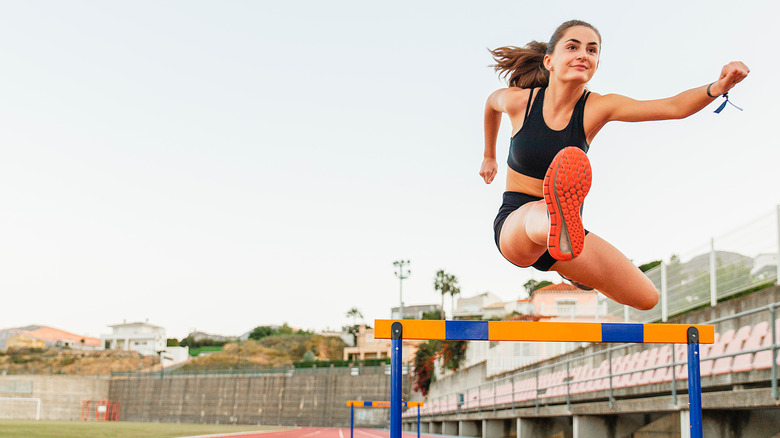 Woman jumping over a hurdle