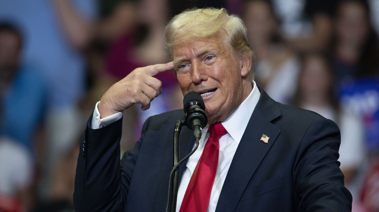 Donald Trump pointing to his head at a rally