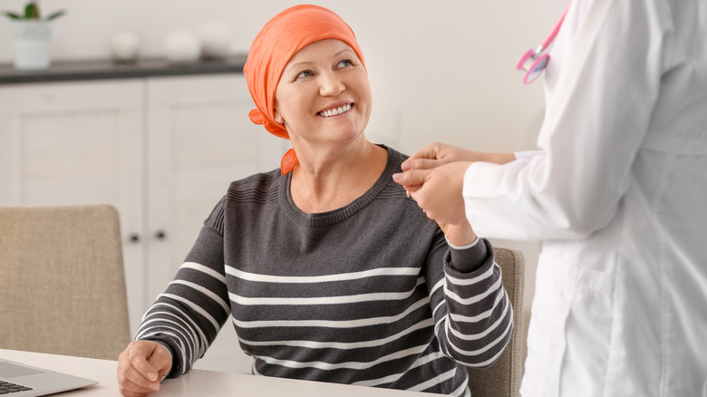 Doctor holding hand of smiling cancer patient