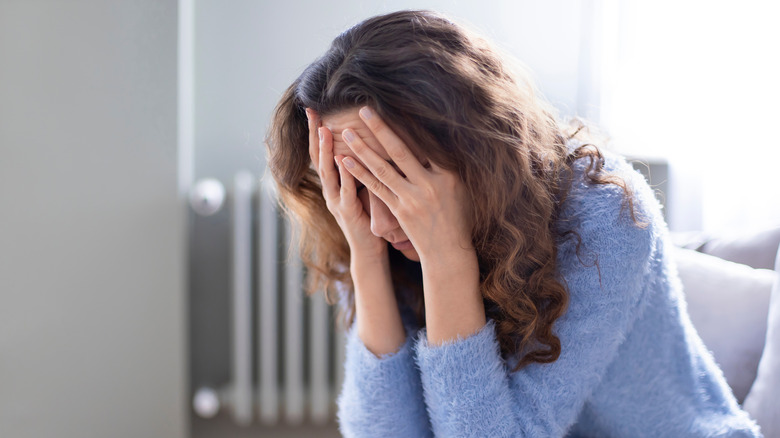 Sad woman sits with her face in her hands