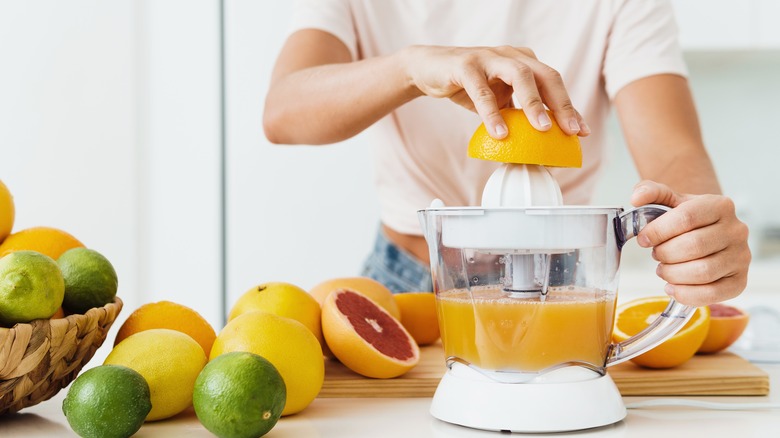 person squeezing citrus fruit into pitcher