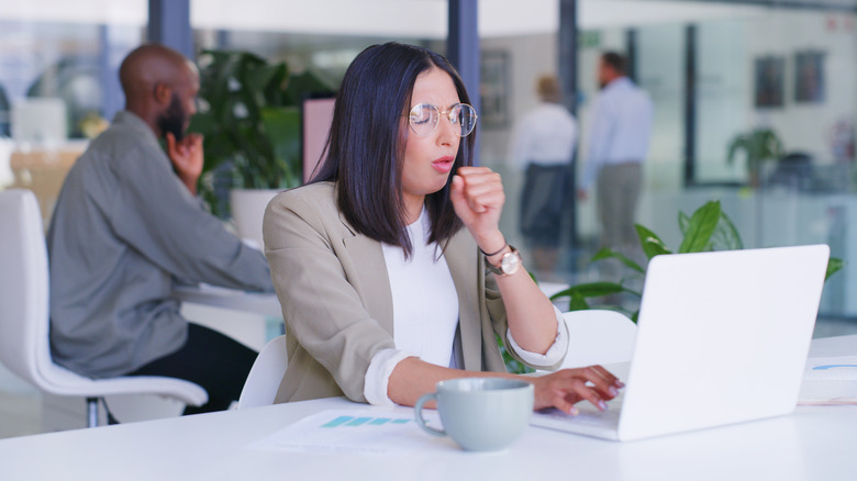 Woman in office coughing