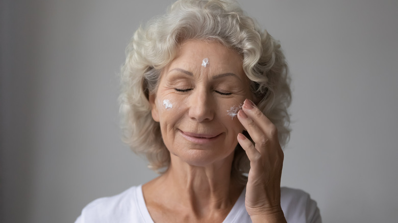 Older woman dabbing lotion on her face