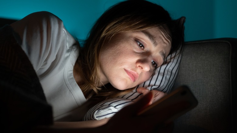 depressed woman using phone in bed