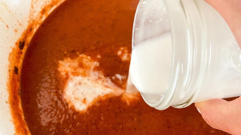 coconut milk poured into tomato soup
