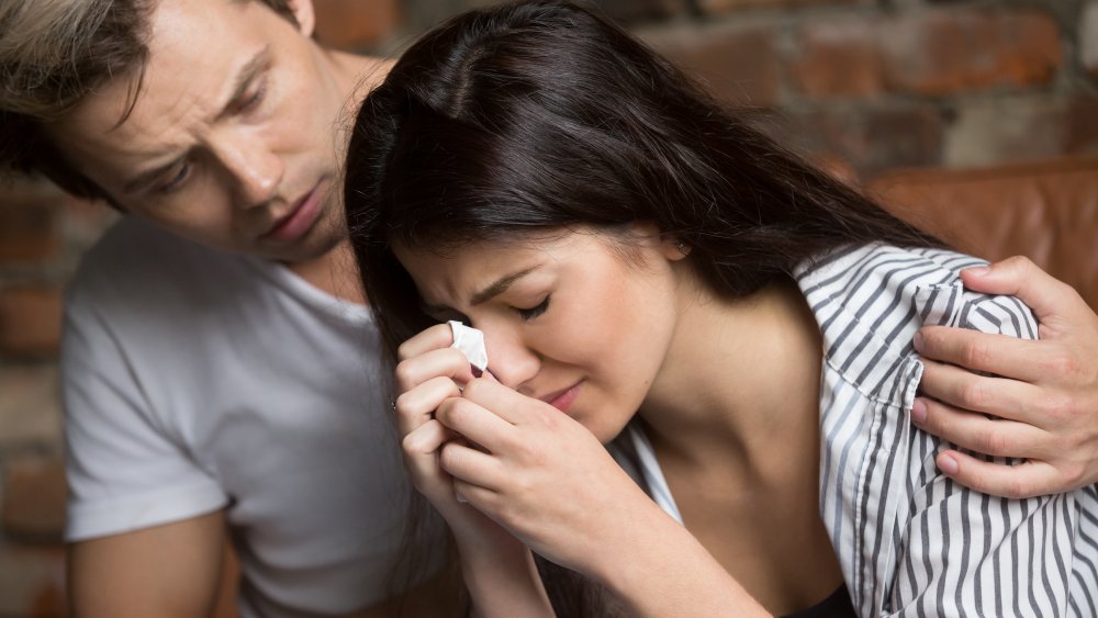 Man comforting distressed, crying woman
