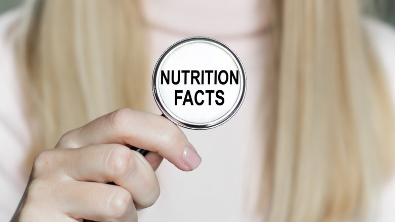 Woman hold a circle that says "Nutritional Facts"