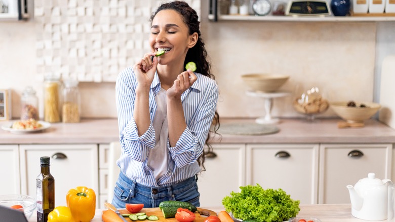 young woman eating slices of cucumber