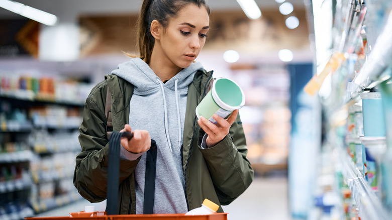 woman looking at yogurt container label in store