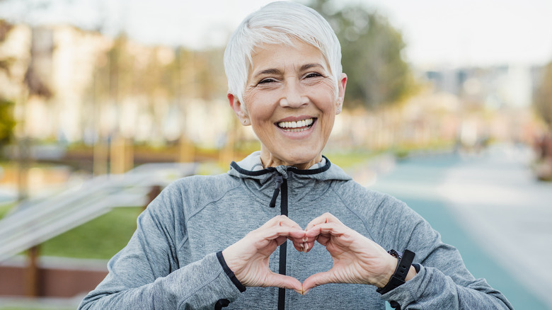 older woman doing heart hands while exercising