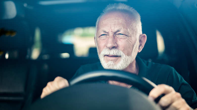 older man squinting while driving