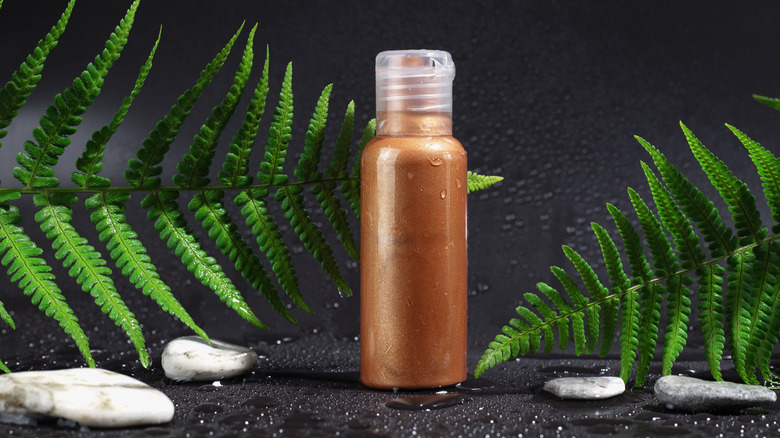 A bottle of self-tanner by plants