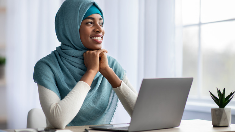 Smiling woman in hijab at laptop