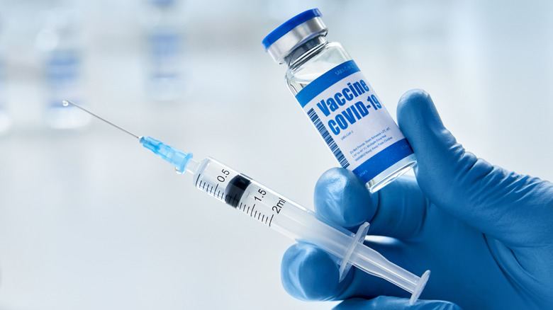 Close up of gloved hand holding a syringe and COVID-19 vaccine vial