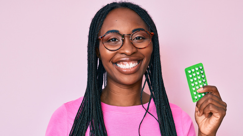 Black woman holding a pack of birth control pills