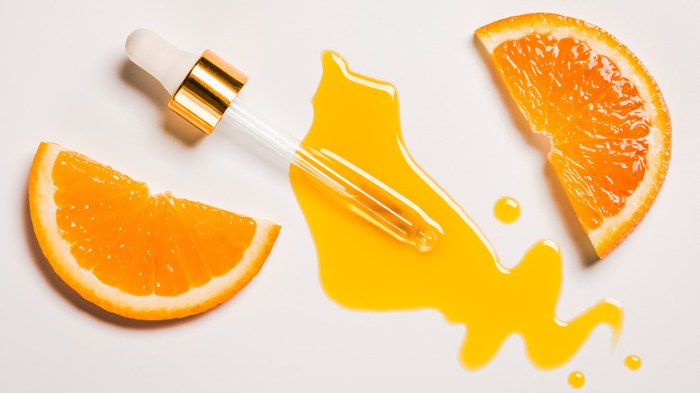 pieces of an orange with a dropper of vitamin C serum