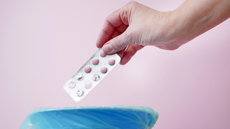 Hand dropping pills packet into trash