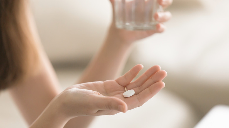 Hands holding pill and water