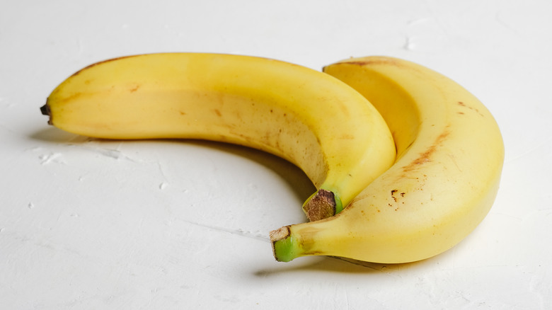 Two bananas on white surface