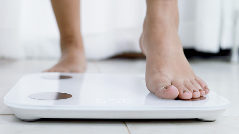 close-up of a woman's foot stepping onto a body fat scale