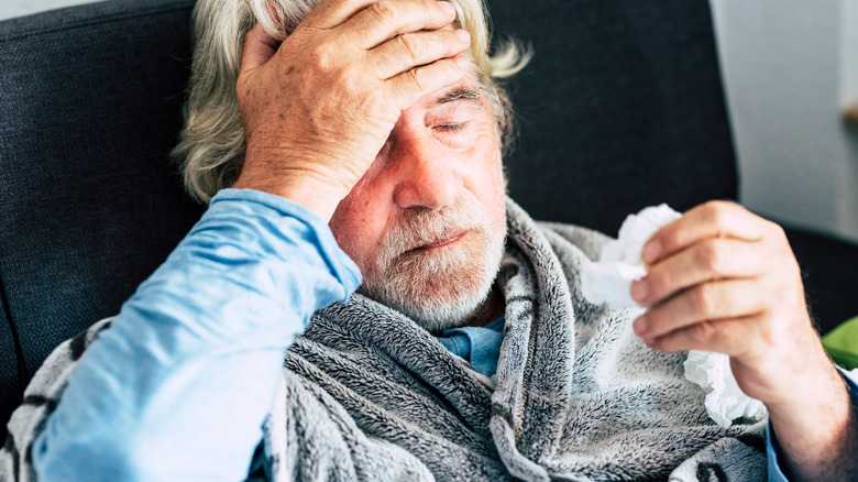 Sick man lies back on couch