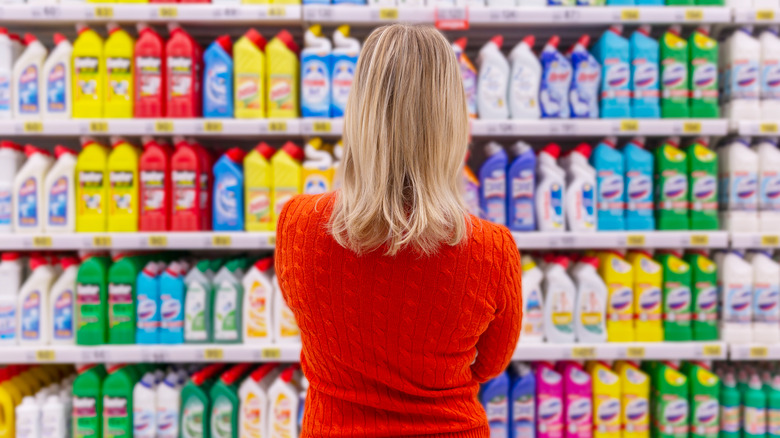 woman standing in front of cleaning supply section of supermarket