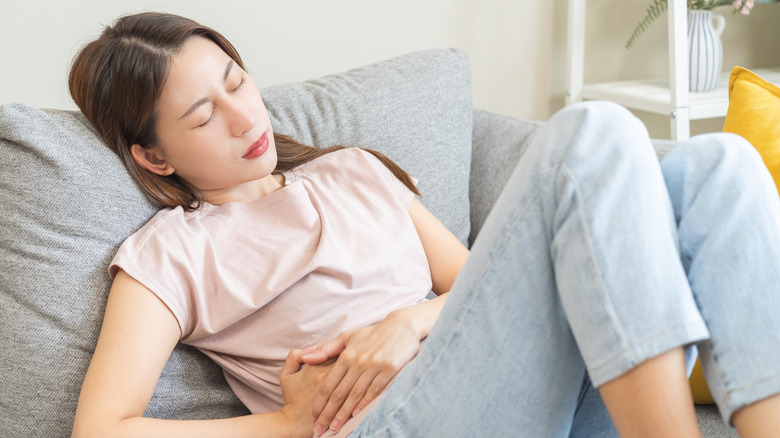 A woman lying on her couch with gas and bloating