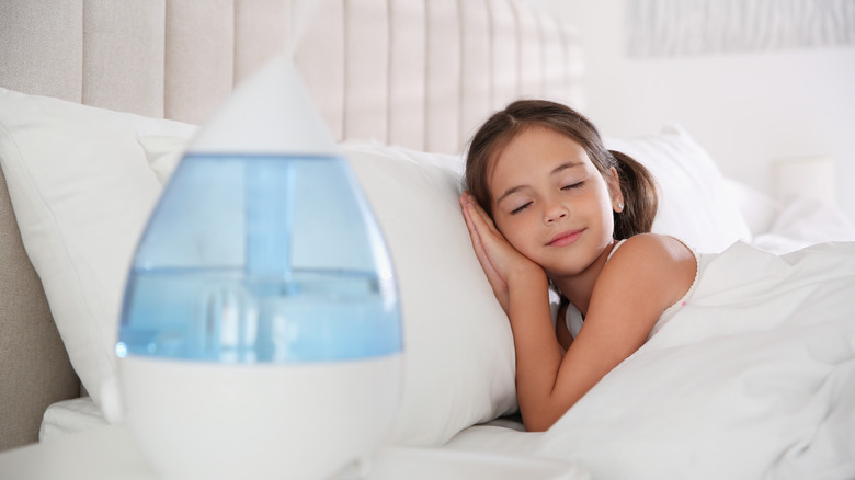 Young smiling child asleep in bed next to a humidifier