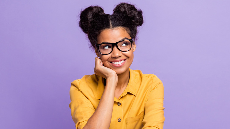 Black woman with two buns thinking and smiling