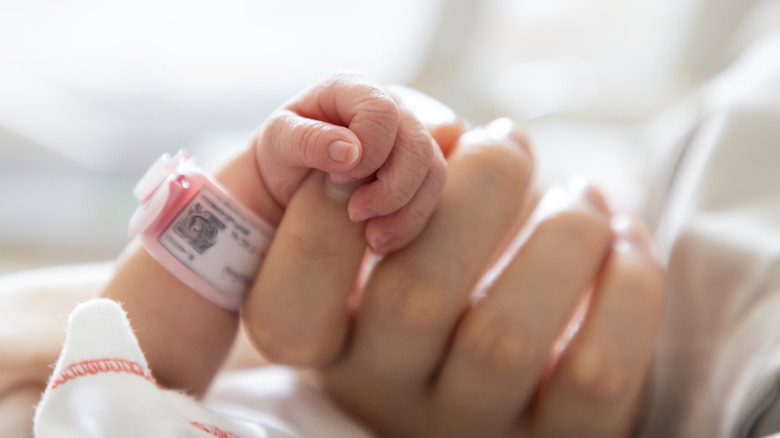 Newborn baby hand holding mom's index finger