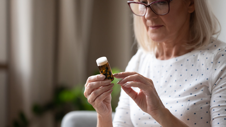 older woman checking pill bottle