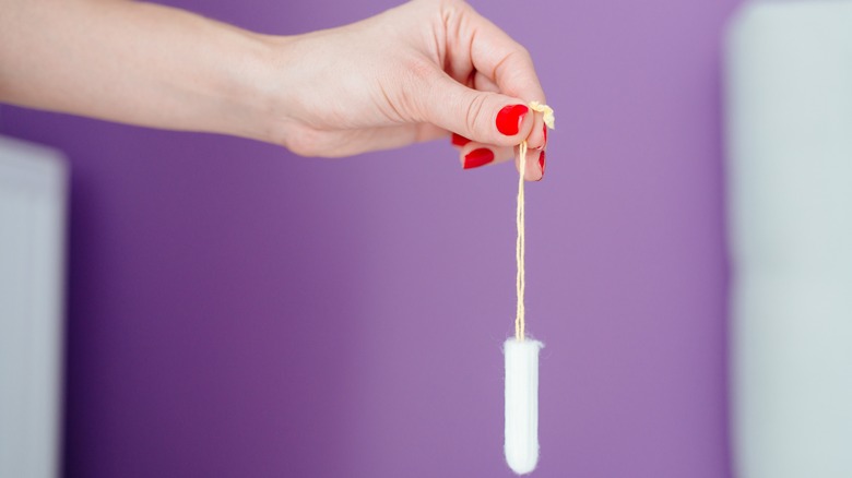 Tampon dangling from pinched fingers