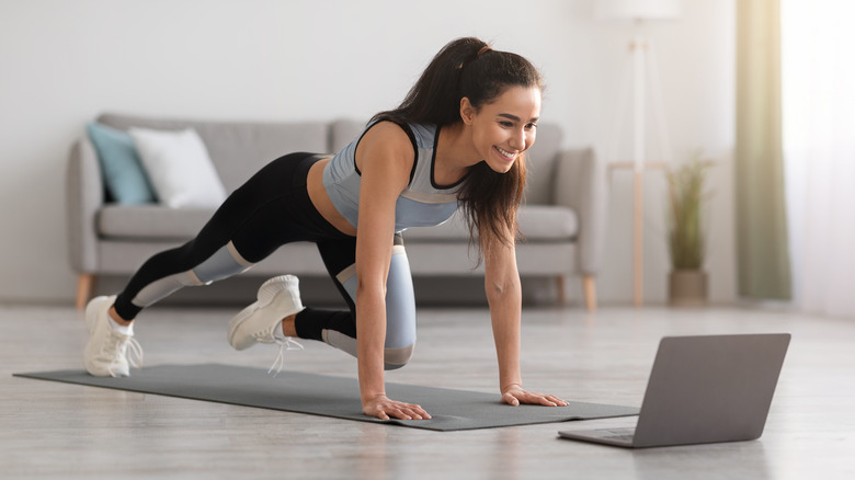 young brunette showing off a modified plank pose in her living room 