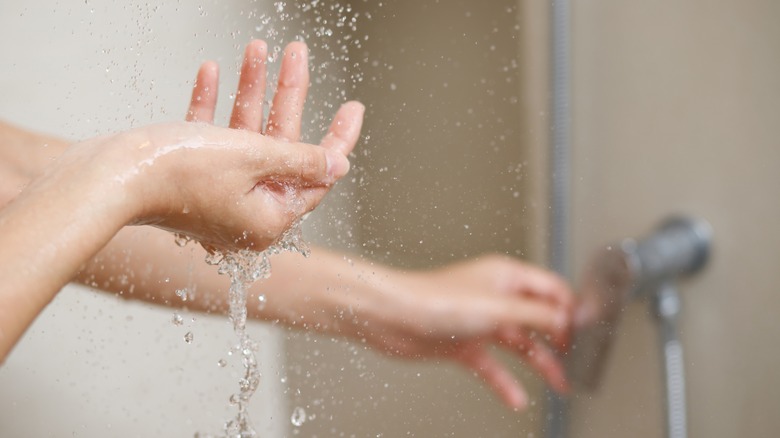 woman's hand tests the temperature of the shower water