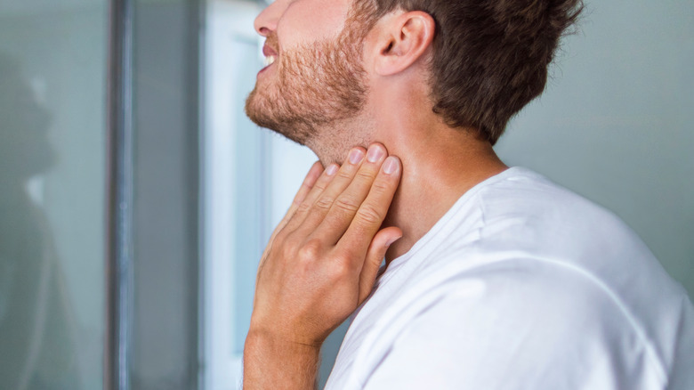man checking his neck for skin cancer