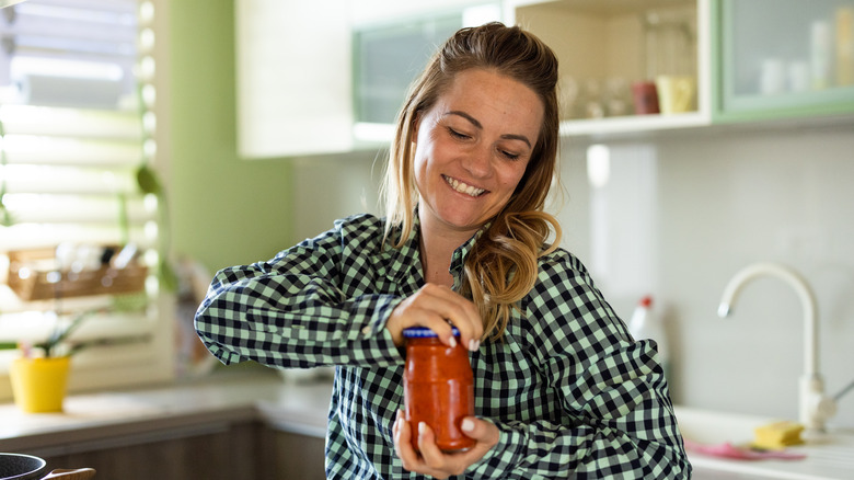 Hands opening sauce jar