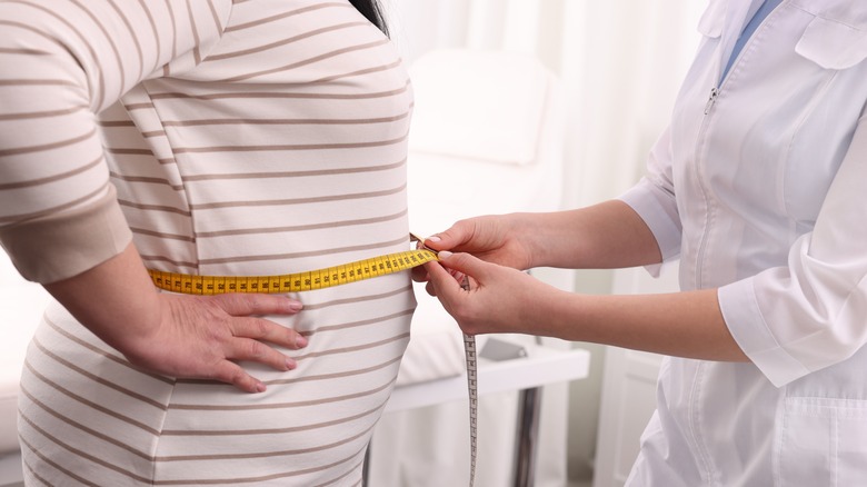 woman measuring another woman's waist circumference