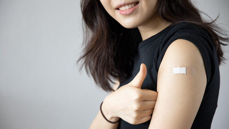 Woman making thumbs up gesture after vaccination