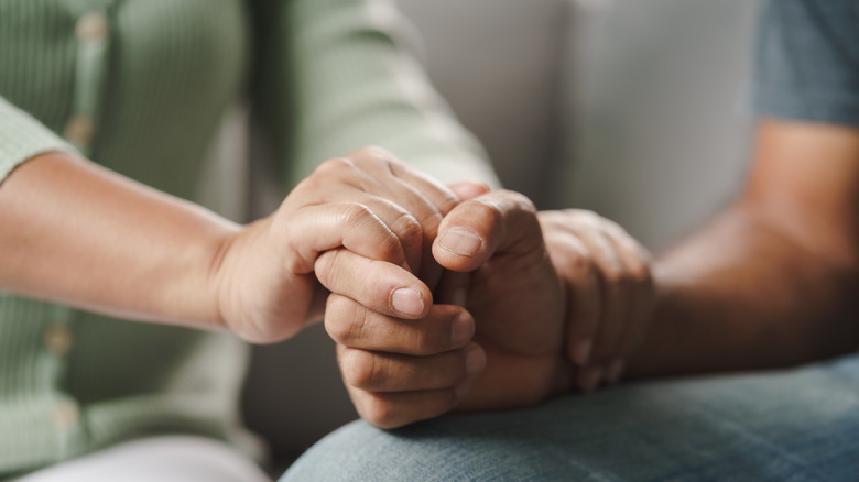 Two people holding hands in support