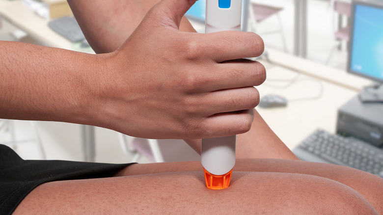 A woman injecting an EpiPen into her thigh 