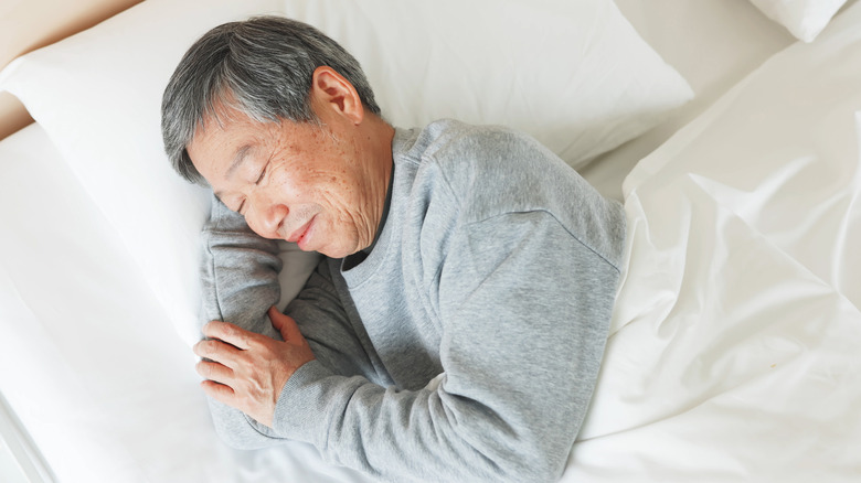 Man smiling sleeping on his side in bed