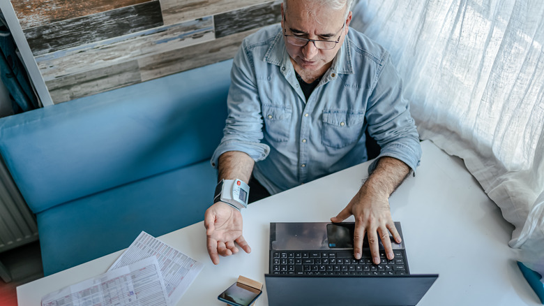 man logging his health records into a laptop