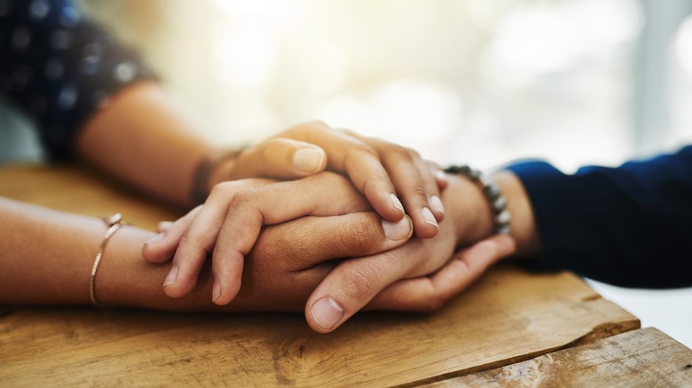 two people holding hands across table