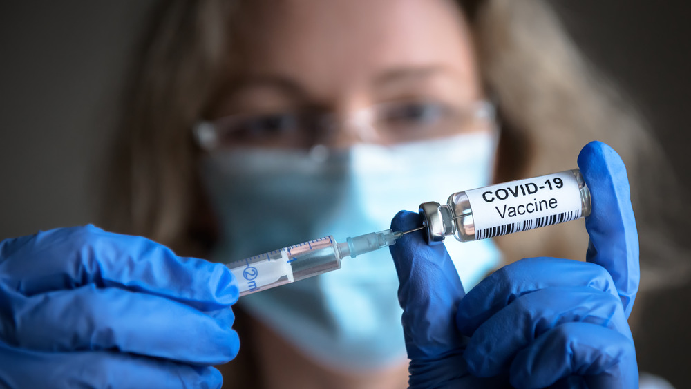 A close up of a vaccine bottle concept held up alongside a needle