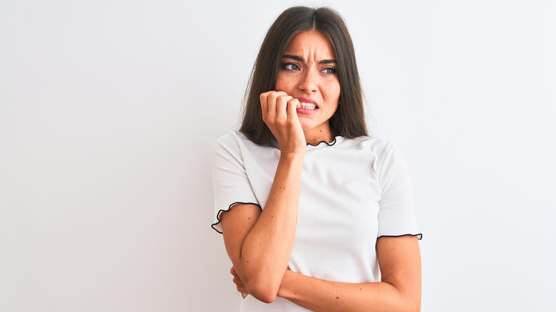 woman biting her nails and looking anxious