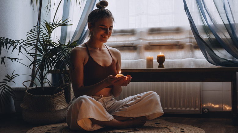 woman sitting in a meditative position with a candle in her hand