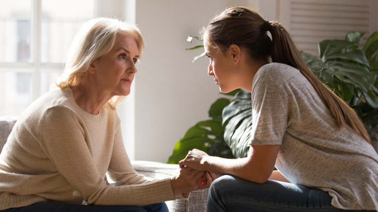 two women hold hands in conversation