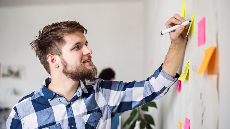 man using left hand to write on white board