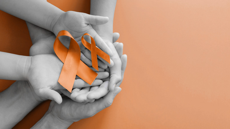 hands holding MS orange ribbons